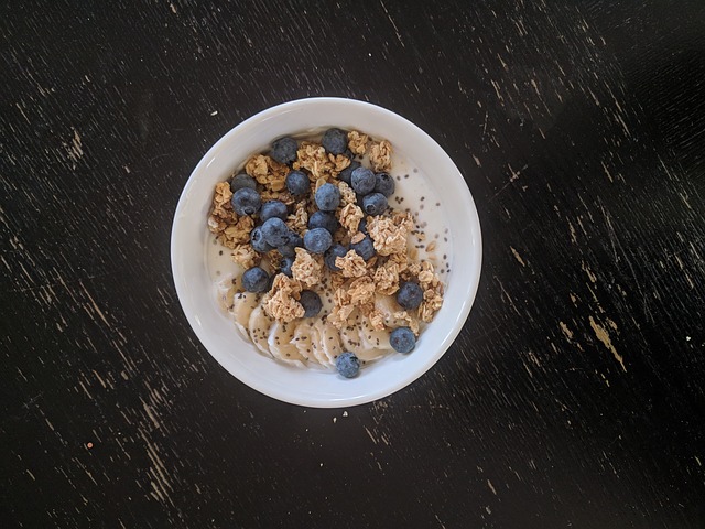 yogurt senza lattosio in scodella, con cereali, banana, kiwi e mirtilli